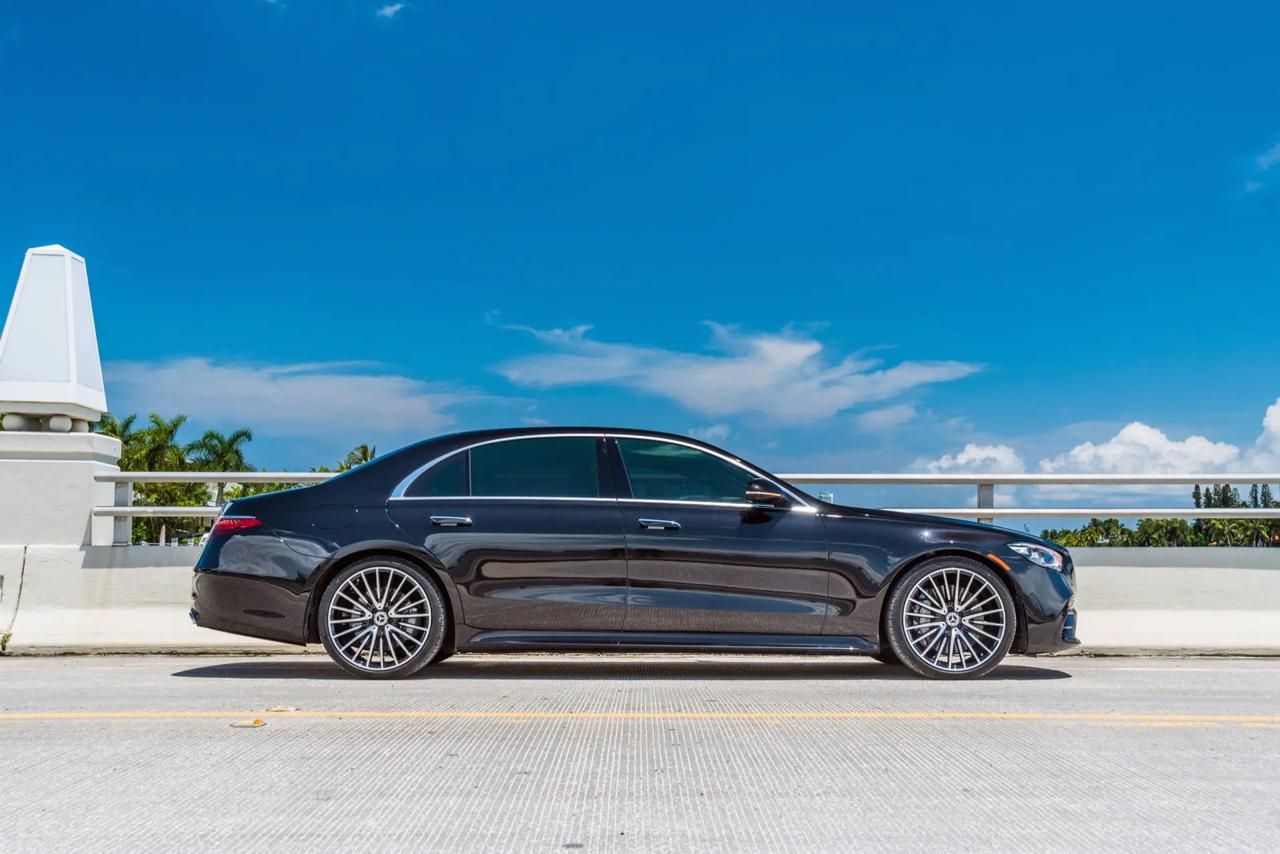 Black luxury sedan crossing a South Florida bridge under a blue sky