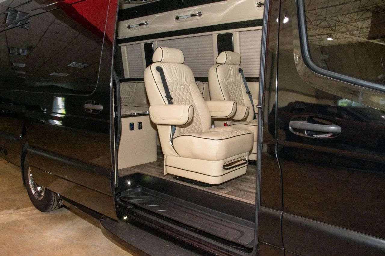 Cream leather captain’s chairs inside an Aura Palm Sprinter with its side door open