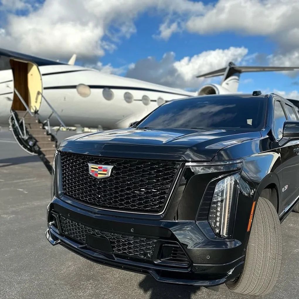 Black Aura Palm SUV parked beside a private jet with its stairs lowered